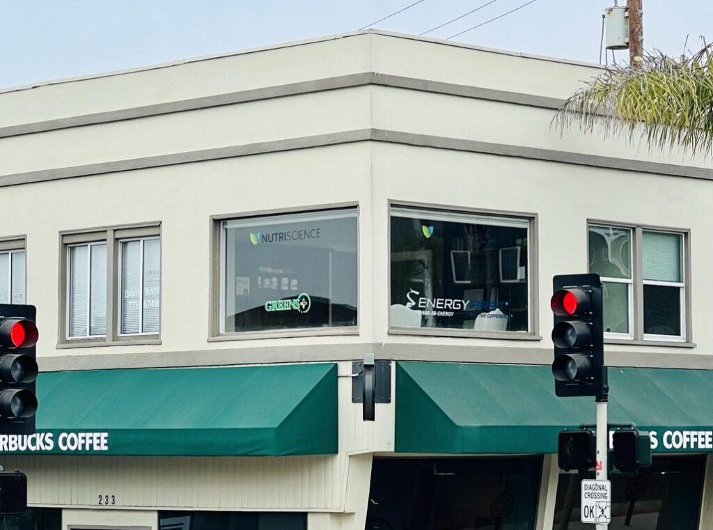 The NutriScience office in Manhattan Beach, with the NutriScience, Greens Plus and EnergyFirst marks in the corner windows above a Starbucks